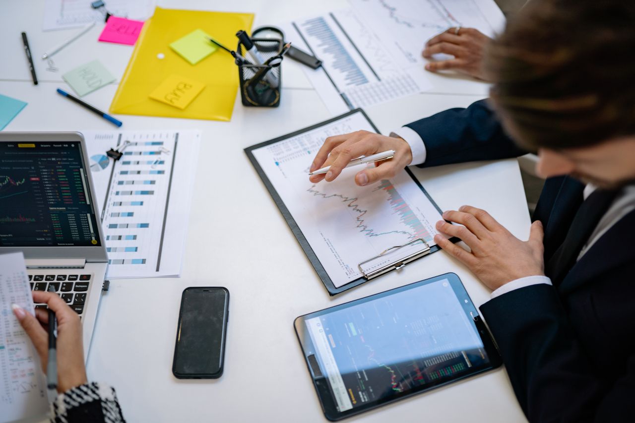 An office team reviews financial charts and digital data on tablets.